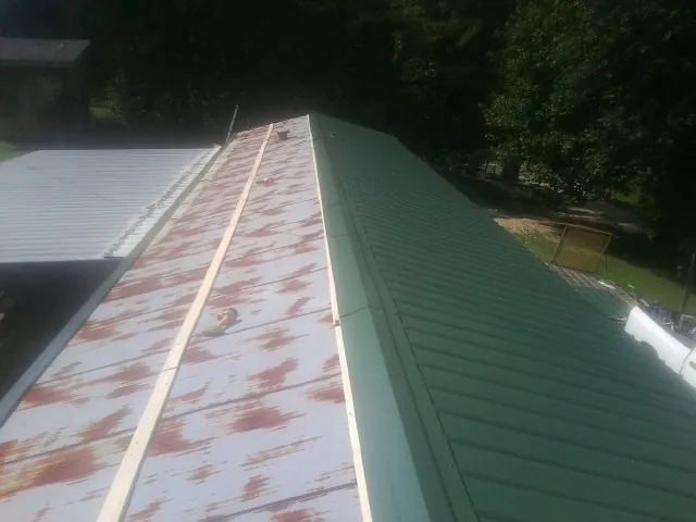 Old rusted panels beside newly installed green metal roofing — Wind Damage Roof Repair by Roofing Brothers in Alapaha