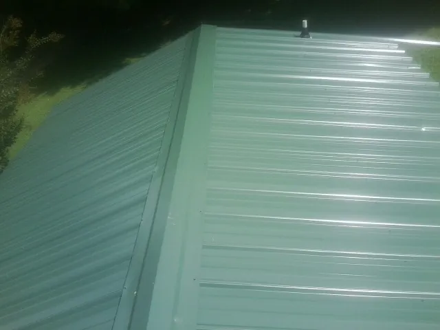 New green metal panels meeting at the ridge of a roof — Flat Roof Repair work by our crew in Alapaha