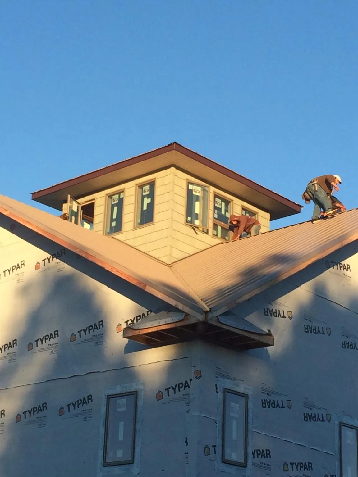 Roofers working around a rooftop cupola on a new metal roof at sunset — Roof Waterproofing in Alapaha by Roofing Brothers